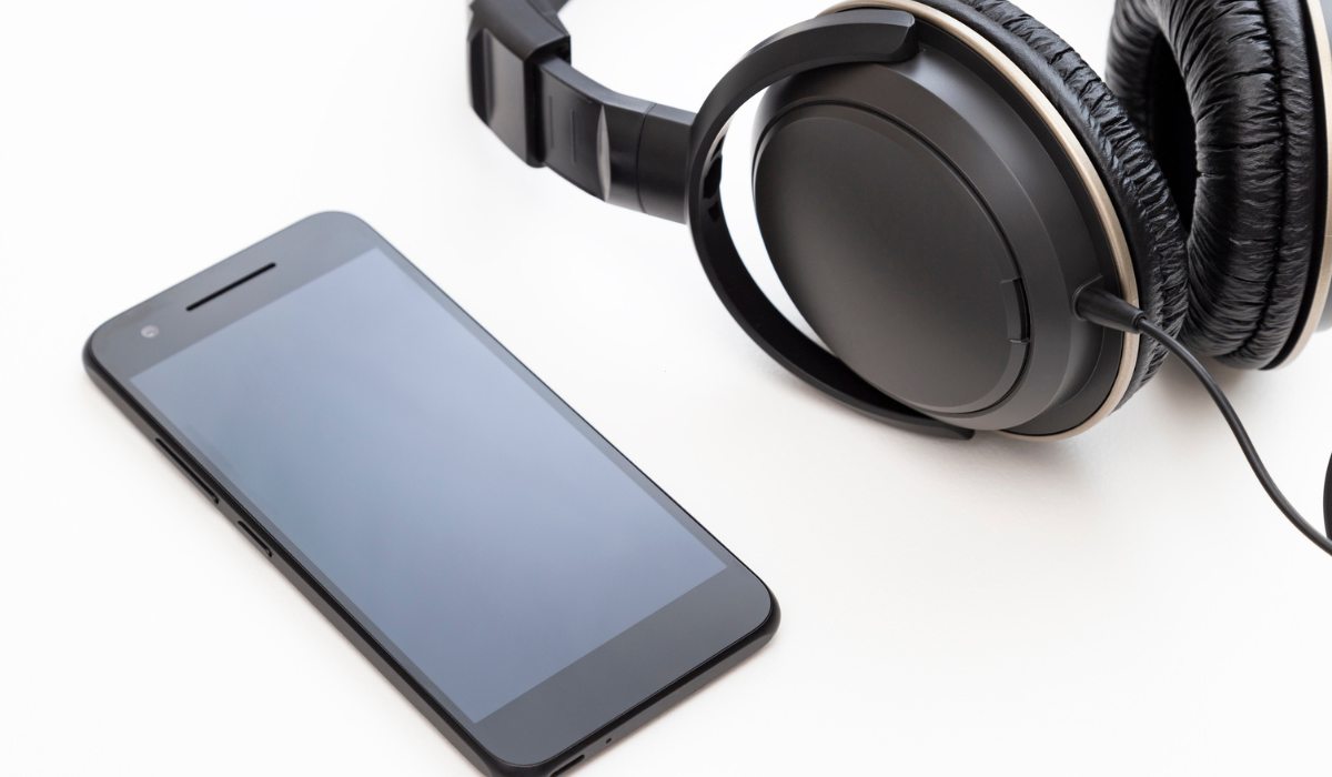 Técnico limpiando la malla de un altavoz móvil con herramientas de precisión y microscopio