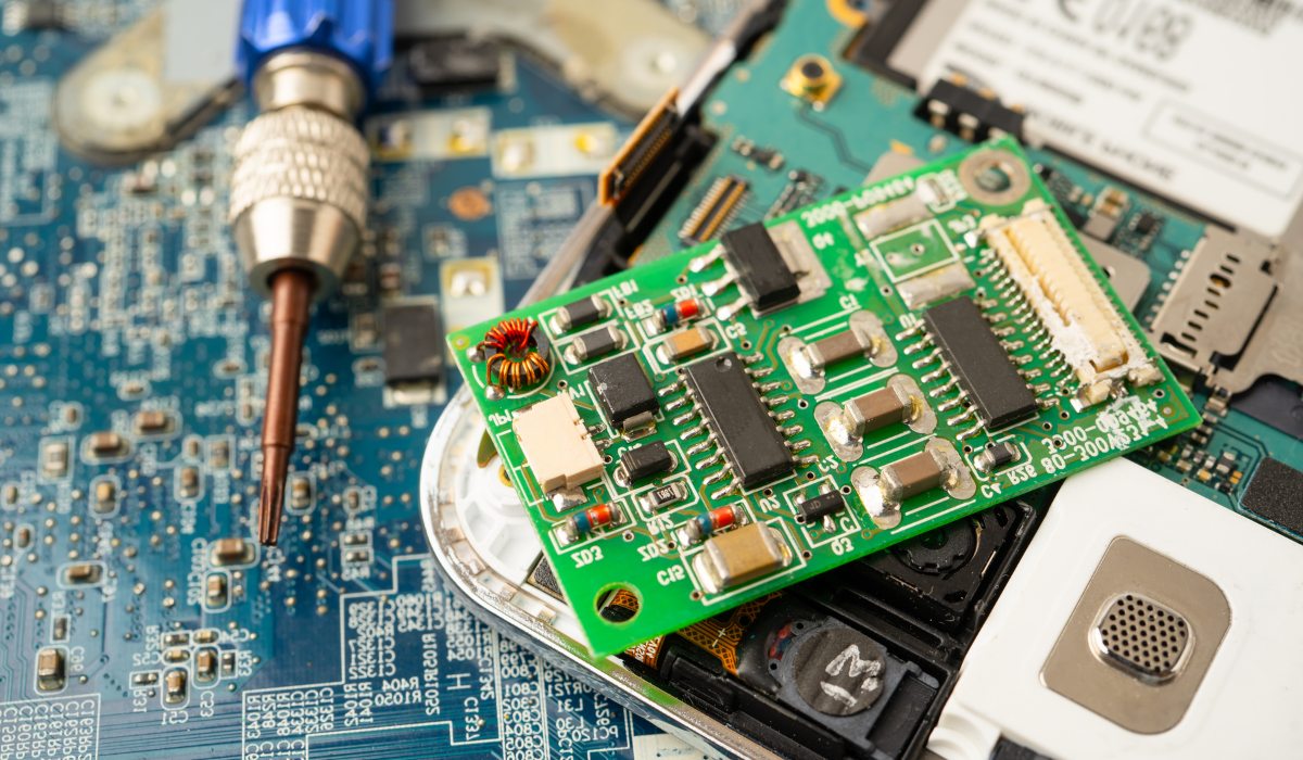 Técnico midiendo caídas de tensión en placa base bajo microscopio con multímetro profesional