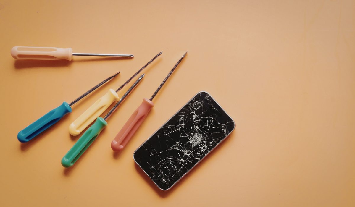 Técnico profesional consultando esquemáticos oficiales digitales mientras realiza una microsoldadura en placa base