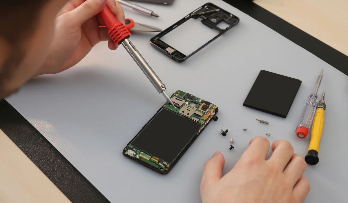 Técnico reparando daños en placa base causados por tornillos mal ubicados bajo microscopio