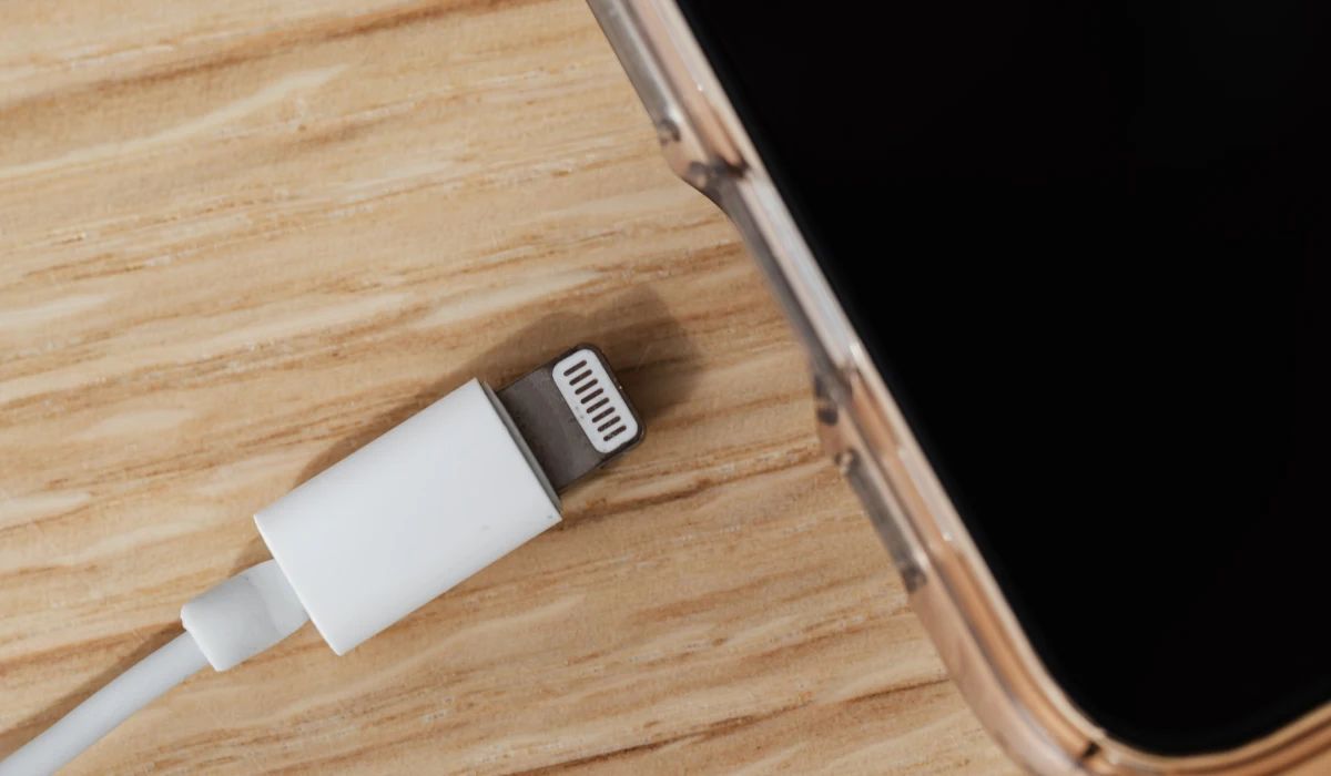 Técnico retirando pelusa compactada de un puerto USB-C con herramientas de precisión bajo microscopio