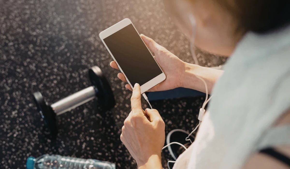 Técnico de reparaciones limpiando el puerto jack de un smartphone con microscopio y pinzas de precisión