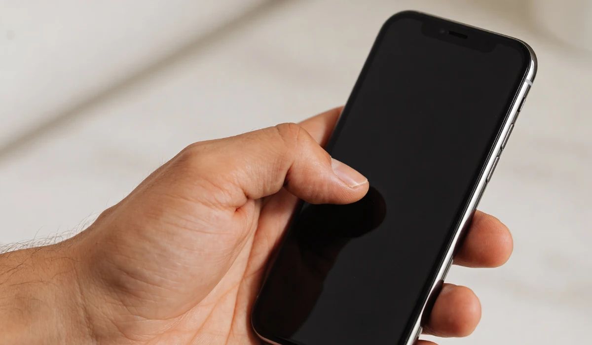 Técnico profesional midiendo el voltaje de una batería de iPhone degradada en un taller de microsoldadura